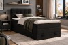 Stilvolles Boxspringbett in Dunkelgrau mit Cord-Struktur und grüner Wohndecke.